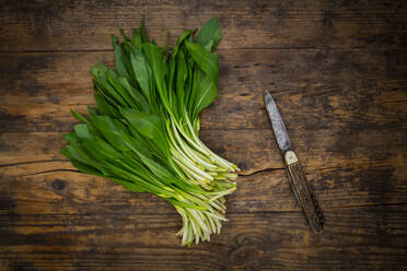 Fresh ramson and kitchen knife lying on wooden surface - LVF09286