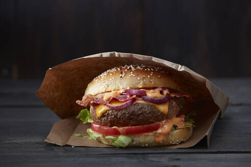 Studioaufnahme eines verzehrfertigen Hamburgers in einer Papiertüte - KSWF02359