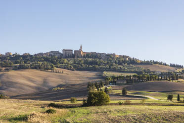 Italien, Toskana, Pienza, Hügellandschaft im Sommer mit Stadtrand im Hintergrund - FOF13625