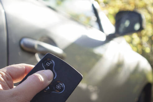 Hand einer Frau, die ihr Auto mit einer Schlüsselkarte verschließt - MAMF02703