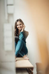 Happy businesswoman with tablet PC sitting cross-legged in home office - JOSEF17662