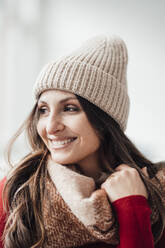 Happy woman wearing knit hat in front of wall - JOSEF17668