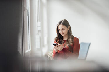 Lächelnde Geschäftsfrau mit Smartphone im Büro - JOSEF17670