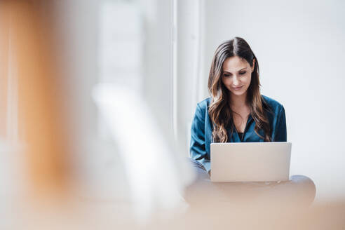 Businesswoman working on laptop at home office - JOSEF17705