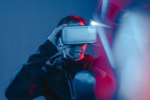 Man wearing virtual reality simulators with neon lights on face - YTF00662