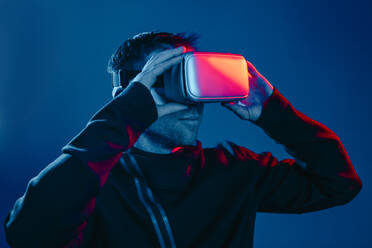 Man wearing virtual reality simulators in front of wall - YTF00663