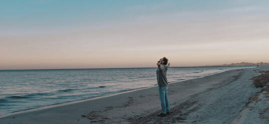 Mature man standing with arms outstretched at beach - SIPF02893