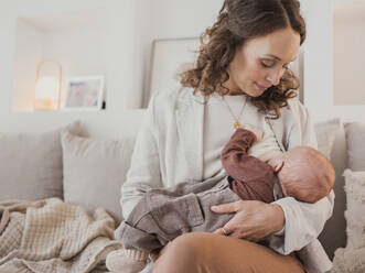 Woman breastfeeding son on sofa at home - MFF09287