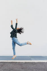 Young woman jumping in front of wall - MEUF08971