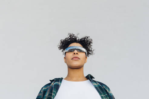 Young woman wearing smart glasses in front of wall - MEUF08982