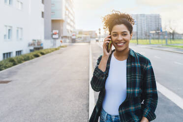 Glückliche junge Frau, die mit einem Smartphone telefoniert - MEUF08988