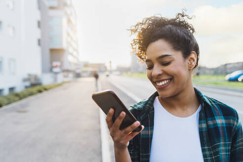 Happy young woman using smart phone on road - MEUF08991