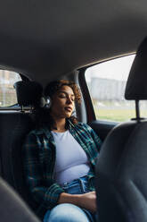 Junge Frau mit geschlossenen Augen entspannt im Auto - MEUF08993