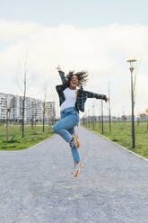 Cheerful woman jumping on footpath - MEUF08996