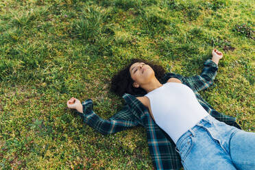 Young woman with eyes closed relaxing in grass - MEUF09006