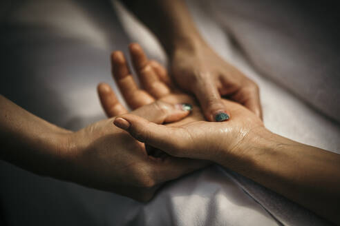 Massage therapist massaging woman's hand - MJRF00920