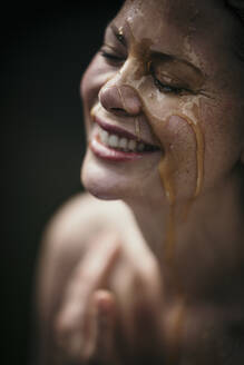 Glückliche Frau mit Flüssigkeit im Gesicht im Wellnessbereich - MJRF00926