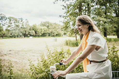 Happy woman enjoying riding bicycle - MJRF00931