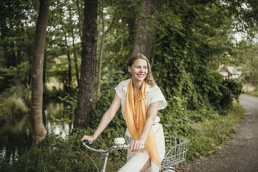 Glückliche Frau fährt Fahrrad auf dem Fußweg - MJRF00932