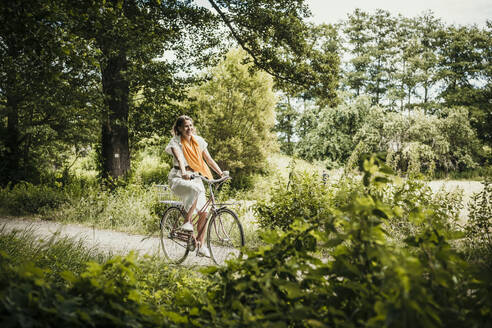 Frau fährt Fahrrad inmitten von Bäumen - MJRF00933
