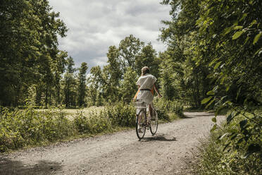 Woman riding cycle on dirt road - MJRF00934