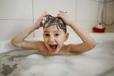 Happy boy having fun in bathtub at home - ANAF01121