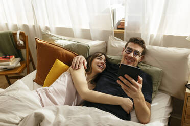 Ehepaar schaut auf einen Tablet-PC, der zu Hause im Bett liegt - EBSF02989