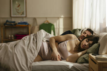 Man and woman holding hands sleeping in bedroom - EBSF02993