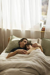 Affectionate couple sleeping in bed at home together - EBSF02995