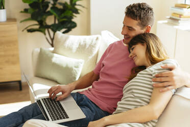 Girlfriend leaning head on boyfriend's shoulder using laptop at home - EBSF03039
