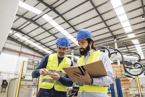 Ingenieur im Gespräch über ein Maschinenteil mit einem Kollegen in der Industrie - JCCMF09937