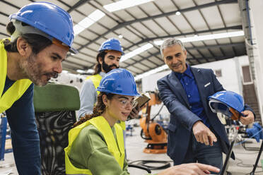 Geschäftsmann gestikuliert und diskutiert mit Kollegen über Laptop in der Industrie - JCCMF09944