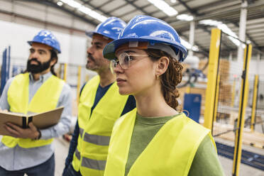 Ingenieure mit Schutzhelmen bei einer Diskussion in der Industrie - JCCMF09948