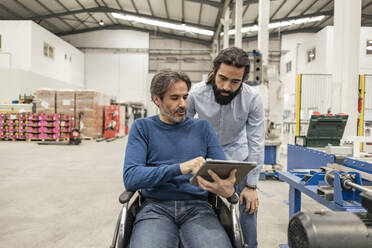 Reifer Geschäftsmann im Gespräch mit einem Kollegen über einen Tablet-PC in einer Fabrik - JCCMF09980