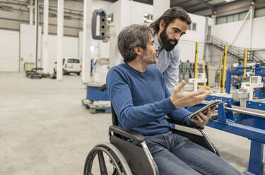 Behinderter Ingenieur im Gespräch mit einem Kollegen in der Industrie - JCCMF09981