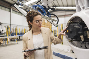 Junger Ingenieur untersucht Roboterarm in der Industrie - JCCMF09984