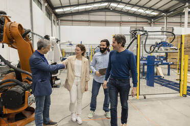 Happy young engineer shaking hands with colleague in robotic industry - JCCMF10031