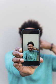 Man showing calling gesture on smart phone at home - PNAF05135