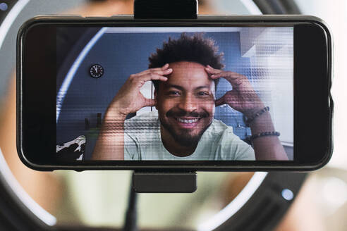 Smart phone screen with smiling influencer making vlog at home - PNAF05149