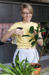 Reife Frau kümmert sich um Pflanzen zu Hause - VYF00957