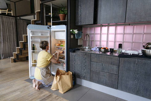 Frau füllt den Kühlschrank zu Hause mit Lebensmitteln - VYF00974