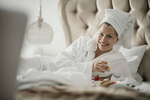 Happy woman enjoying breakfast in bed at home - MJRF00965