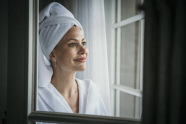 Smiling woman looking out of window - MJRF00971