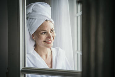 Smiling mature woman with towel on head at home - MJRF00972