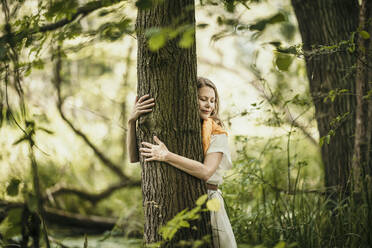 Woman embracing tree in forest - MJRF00978