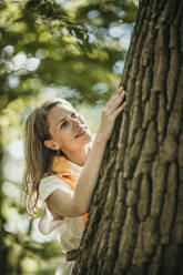 Frau begutachtet Baum im Wald - MJRF00982