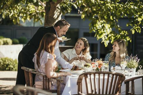 Waiter serving food to women at restaurant - MJRF00990