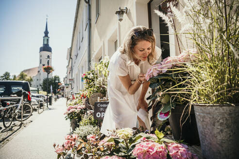 Woman examining plant at flower shop - MJRF00993