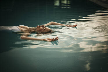 Frau mit erhobenen Armen entspannt im Schwimmbad - MJRF01012