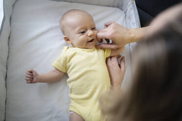 Mutter spielt mit einem kleinen Jungen, der in einem Kinderbett liegt - NJAF00296